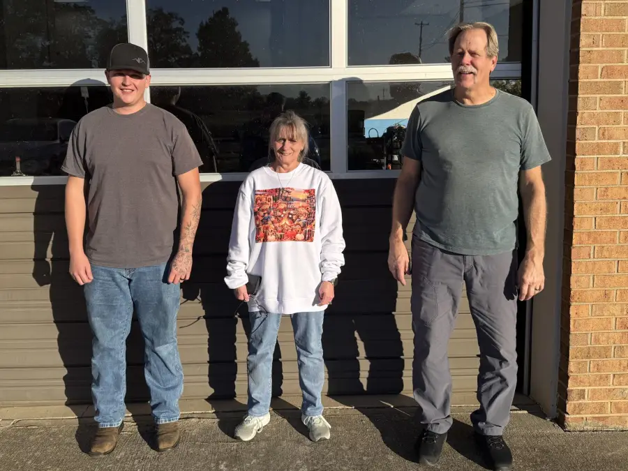 Lance, his wife, and a family member who works at the shop, standing outside the bay door